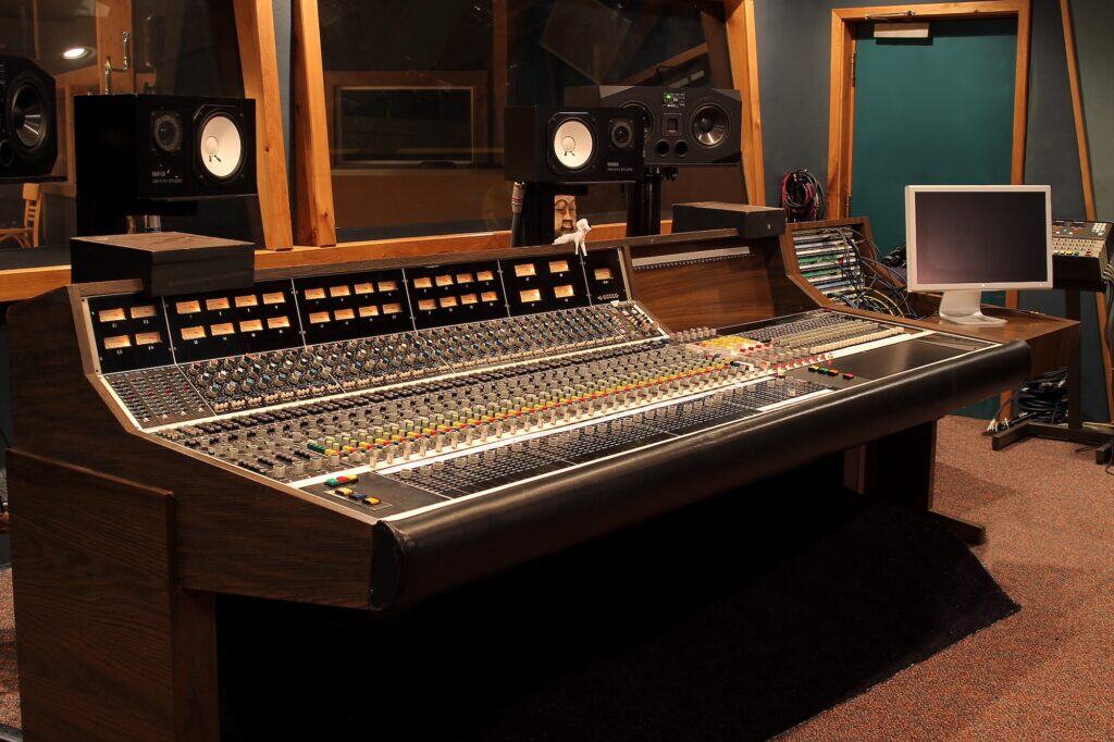 Vintage 1976 API recording console in room with aqua-blue walls, yamaha speakers on bridge, computer monitor in corner