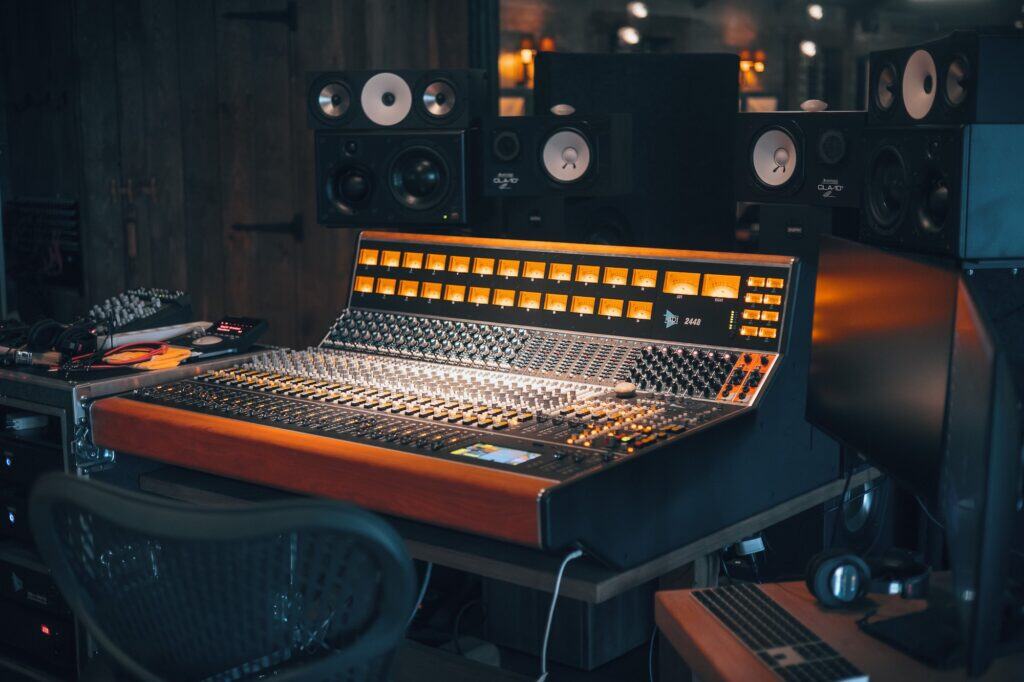 Photo of API 2448 console with speakers in the background. Spotlight on console with dark background.