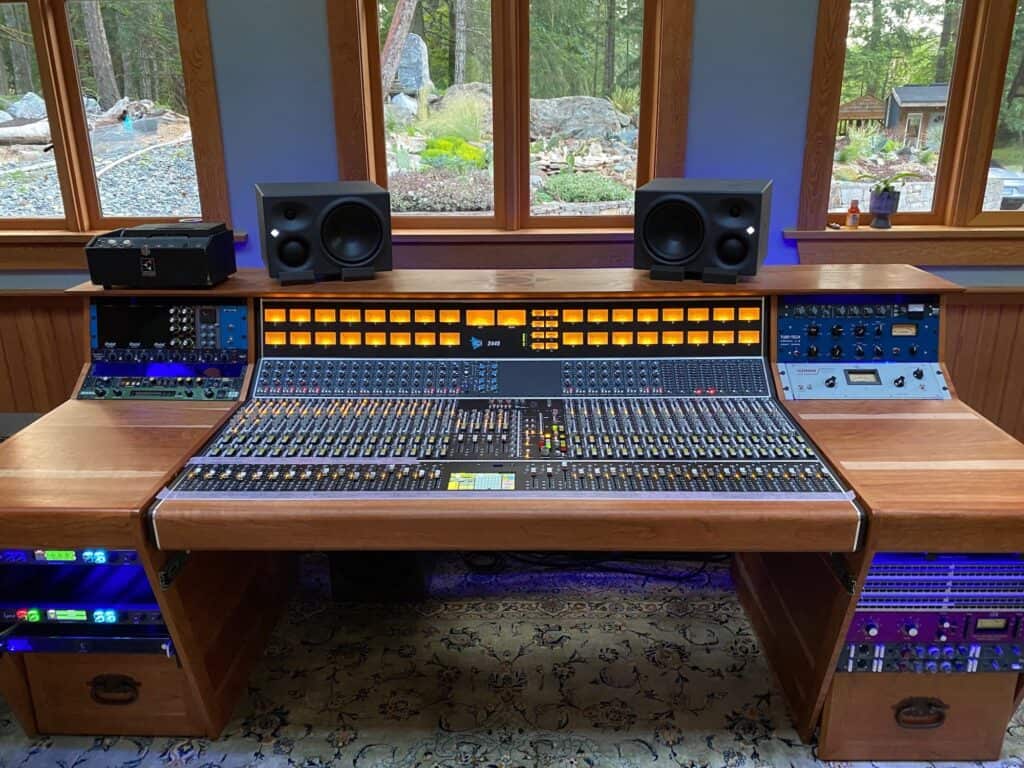 API 2448 console with custom wooden desk in front of a bay of windows, forest outside