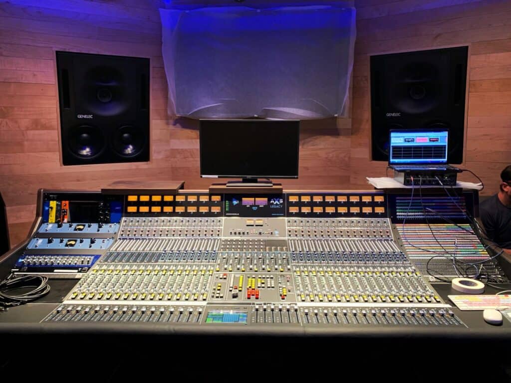 Large recording console in control room with large far-field monitors mounted in the wall